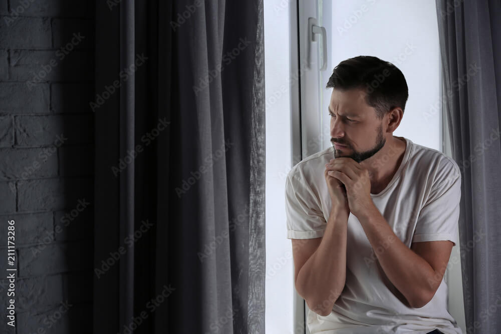 Irrational Risk YOLO Investing: Destroying Your Financial and Mental Health 14 Lonely depressed man near window at home